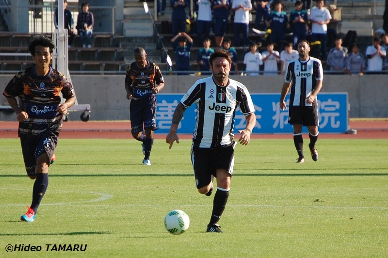 前半にドリブルするスキラッチ。左は斉藤俊秀　[写真]=田丸英生